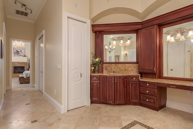 11430 Trotting Down Dr, Odessa, FL 33556 - ensuite bathroom featuring a chandelier, vanity, a glass covered fireplace, crown molding, and tasteful backsplash