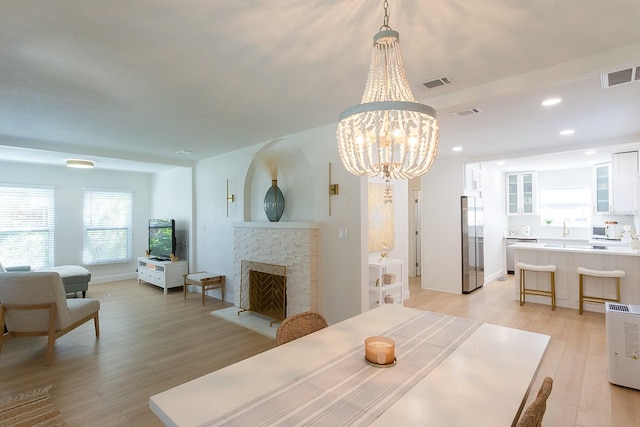 434 77th Ave, St Pete Beach, FL 33706 - dining area featuring light wood-type flooring, a chandelier, a brick fireplace, and recessed lighting
