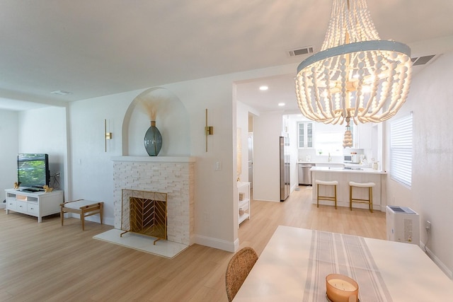 434 77th Ave, St Pete Beach, FL 33706 - dining space featuring a chandelier, light wood-style flooring, a brick fireplace, and recessed lighting