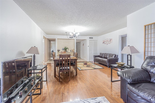 14820 Rue De Bayonne Unit 301, Clearwater, FL 33762 - living room featuring a chandelier, light wood-type flooring, and a textured ceiling