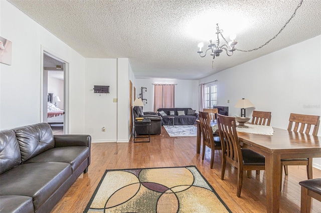 14820 Rue De Bayonne Unit 301, Clearwater, FL 33762 - dining room featuring light wood-style flooring, a chandelier, and a textured ceiling