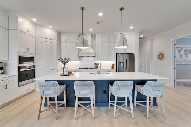 5971 Hidden Branch Dr, Apollo Beach, FL 33572 - kitchen featuring stainless steel appliances, backsplash, an island with sink, light wood-type flooring, and white cabinetry