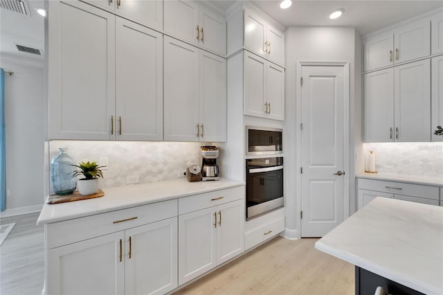 5971 Hidden Branch Dr, Apollo Beach, FL 33572 - kitchen with appliances with stainless steel finishes, light wood-type flooring, decorative backsplash, white cabinetry, and recessed lighting