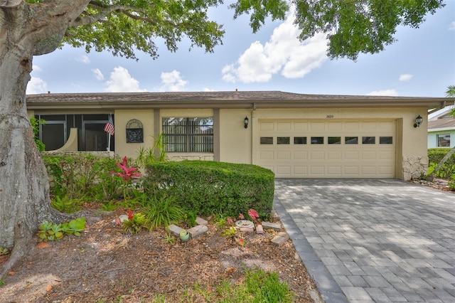 2609 Lancaster Dr, Sun City Center, FL 33573 - view of front of home featuring stucco siding, a garage, and decorative driveway