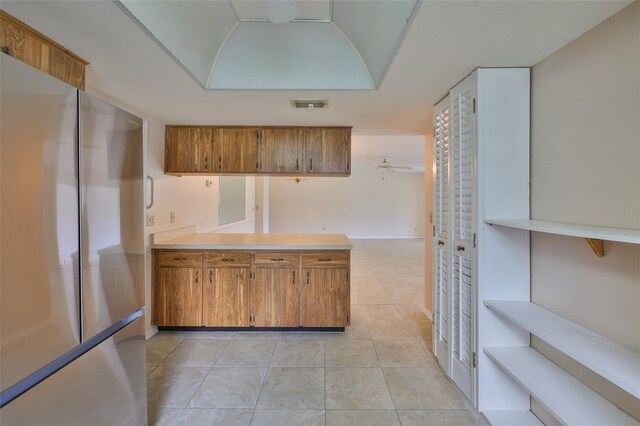 2609 Lancaster Dr, Sun City Center, FL 33573 - kitchen with freestanding refrigerator, brown cabinets, a peninsula, light tile patterned floors, and light countertops