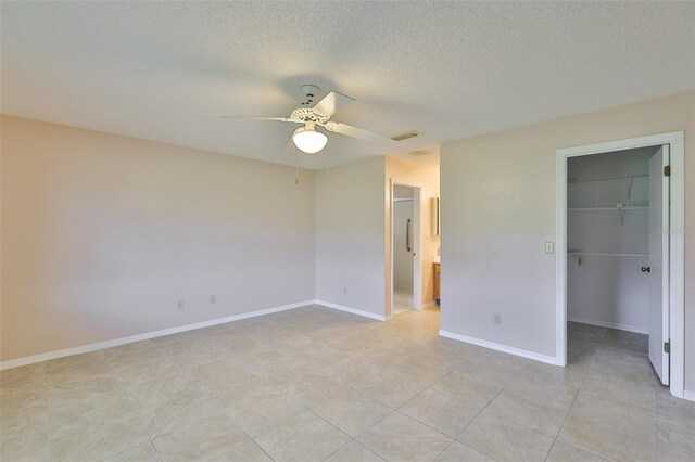 2609 Lancaster Dr, Sun City Center, FL 33573 - unfurnished bedroom featuring a walk in closet, a ceiling fan, a closet, a textured ceiling, and ensuite bath
