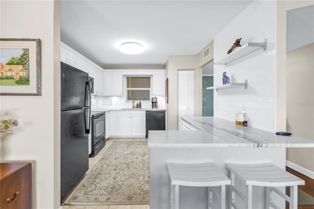 700 Beach Dr NE Unit 602, Saint Petersburg, FL 33701 - kitchen with black appliances, a peninsula, open shelves, white cabinetry, and light stone countertops