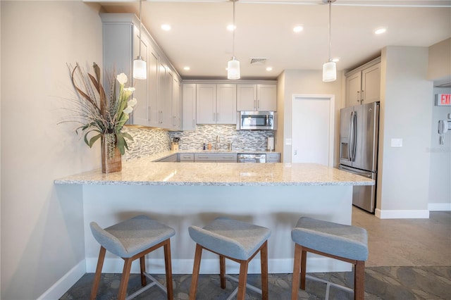 700 Beach Dr NE Unit 602, Saint Petersburg, FL 33701 - kitchen with stainless steel appliances, a peninsula, decorative backsplash, light stone countertops, and a kitchen bar