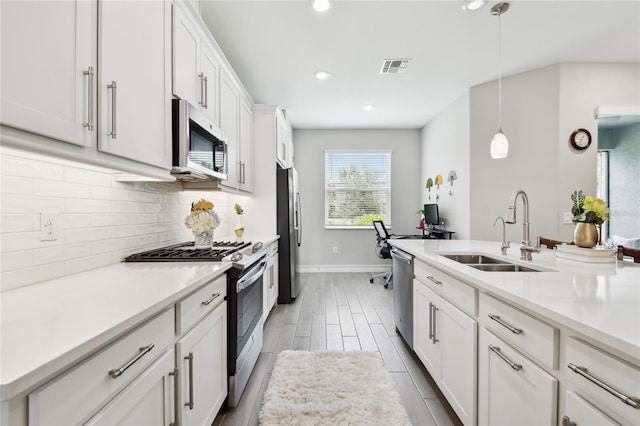 4653 Ancona Way, Wesley Chapel, FL 33543 - kitchen featuring appliances with stainless steel finishes, decorative backsplash, white cabinetry, light countertops, and hanging light fixtures