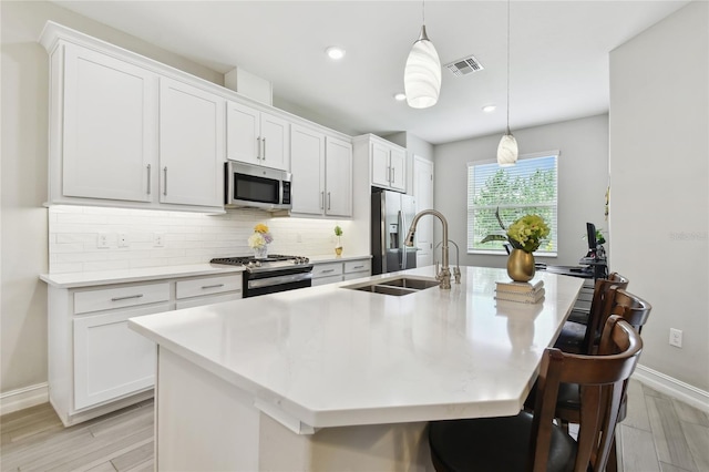 4653 Ancona Way, Wesley Chapel, FL 33543 - kitchen with stainless steel appliances, a kitchen island with sink, backsplash, light wood finished floors, and recessed lighting