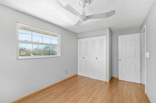 202 Peacock Ln Unit B, Holmes Beach, FL 34217 - unfurnished bedroom with light wood-style floors, a textured ceiling, a closet, and ceiling fan
