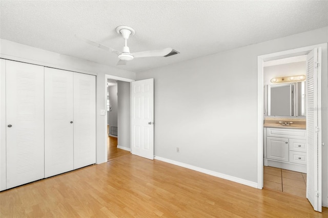 202 Peacock Ln Unit B, Holmes Beach, FL 34217 - unfurnished bedroom featuring light wood-type flooring, a closet, ensuite bathroom, a textured ceiling, and ceiling fan