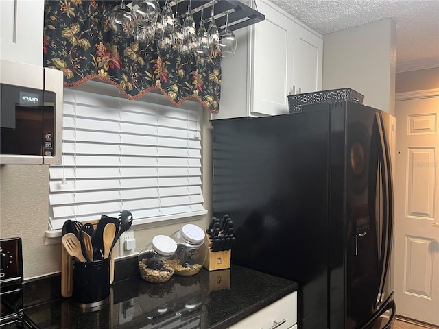 2500 Winding Creek Blvd Unit B105, Clearwater, FL 33761 - kitchen featuring black fridge with ice dispenser, stainless steel microwave, white cabinetry, a textured ceiling, and crown molding