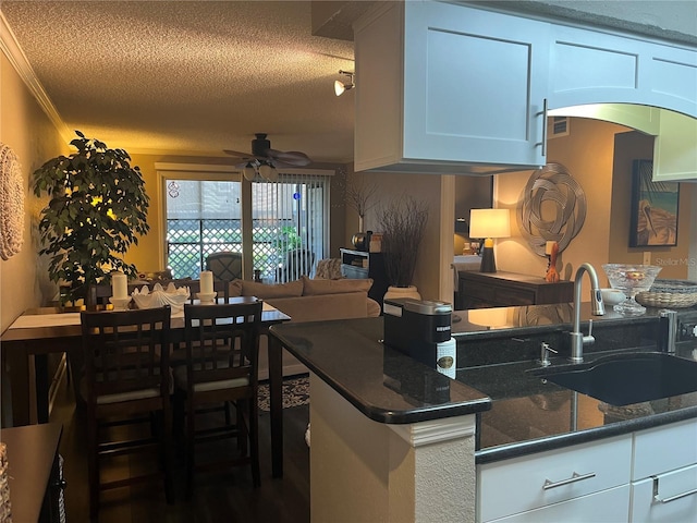 2500 Winding Creek Blvd Unit B105, Clearwater, FL 33761 - kitchen with a ceiling fan, a textured ceiling, arched walkways, white cabinets, and dark stone countertops