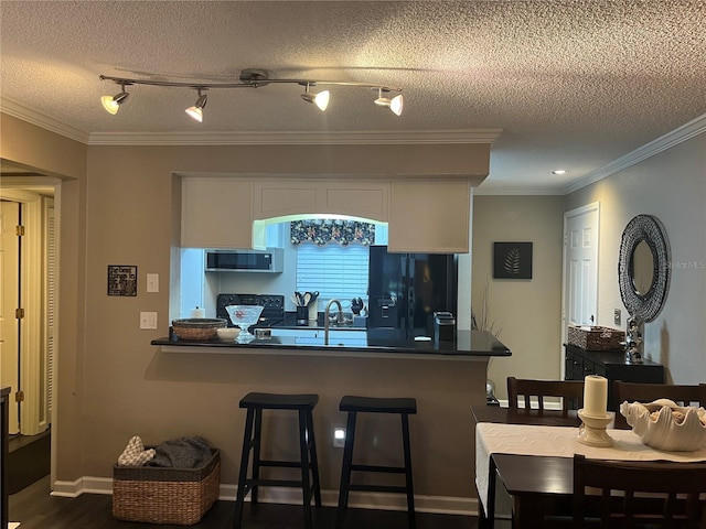 2500 Winding Creek Blvd Unit B105, Clearwater, FL 33761 - kitchen featuring black fridge with ice dispenser, stainless steel microwave, dark countertops, white cabinets, and ornamental molding