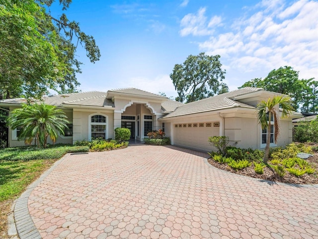 713 Argyle Pl, Temple Terrace, FL 33617 - mediterranean / spanish home featuring an attached garage, decorative driveway, a tile roof, and stucco siding