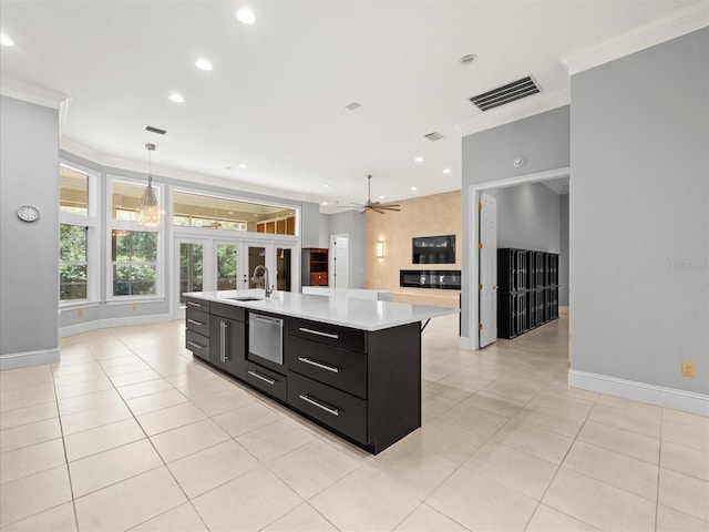 713 Argyle Pl, Temple Terrace, FL 33617 - kitchen with dark cabinets, ornamental molding, light countertops, an island with sink, and light tile patterned floors