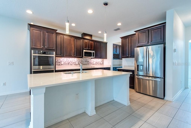 11035 Sage Canyon Dr, Riverview, FL 33578 - kitchen featuring appliances with stainless steel finishes, dark brown cabinets, decorative backsplash, light countertops, and pendant lighting