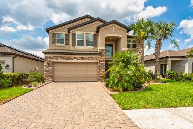 11035 Sage Canyon Dr, Riverview, FL 33578 - view of front facade featuring stucco siding, stone siding, an attached garage, decorative driveway, and a front yard