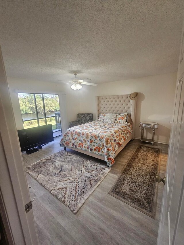 1729 Seascape Cir Unit 102, Tarpon Springs, FL 34689 - bedroom featuring wood finished floors, access to exterior, a textured ceiling, and ceiling fan