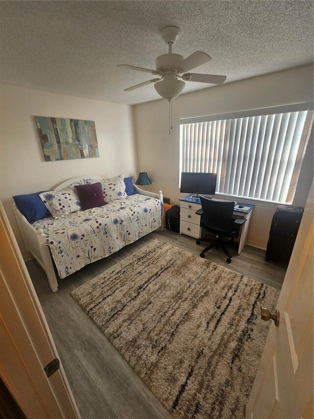 1729 Seascape Cir Unit 102, Tarpon Springs, FL 34689 - bedroom featuring wood finished floors, a desk, a textured ceiling, and a ceiling fan