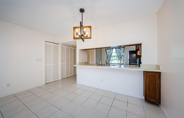 1729 Seascape Cir Unit 102, Tarpon Springs, FL 34689 - kitchen with freestanding refrigerator, a chandelier, decorative light fixtures, light countertops, and light tile patterned floors