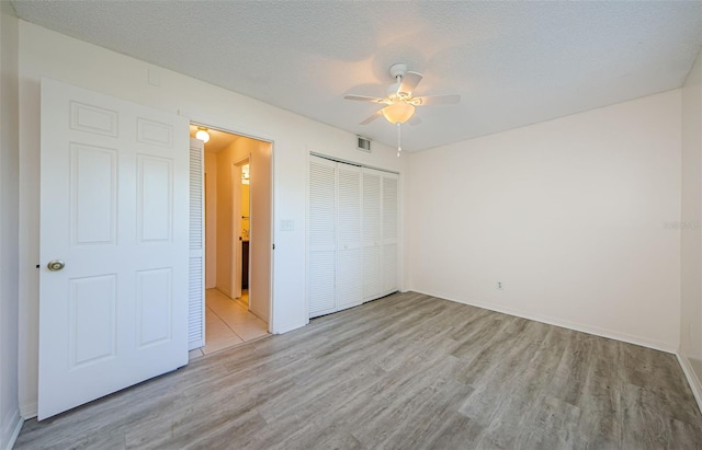 1729 Seascape Cir Unit 102, Tarpon Springs, FL 34689 - unfurnished bedroom with wood finished floors, a closet, a ceiling fan, and a textured ceiling