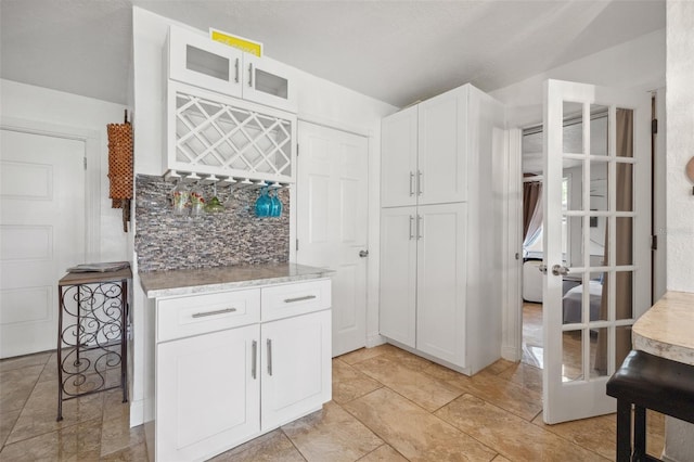 10730 52nd Ave N, Saint Petersburg, FL 33708 - kitchen featuring tasteful backsplash, white cabinetry, glass insert cabinets, and light stone countertops