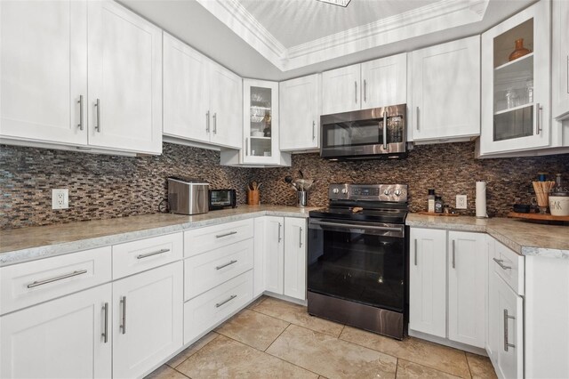 10730 52nd Ave N, Saint Petersburg, FL 33708 - kitchen with stainless steel microwave, electric range oven, light tile patterned flooring, white cabinets, and ornamental molding