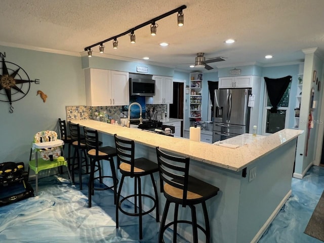 6531 Seaview Blvd, Hudson, FL 34667 - kitchen with appliances with stainless steel finishes, a textured ceiling, a peninsula, backsplash, and white cabinetry