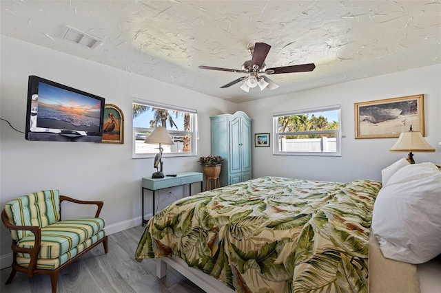 2010 E Vina Del Mar Blvd, St Pete Beach, FL 33706 - bedroom with multiple windows, wood finished floors, and a ceiling fan