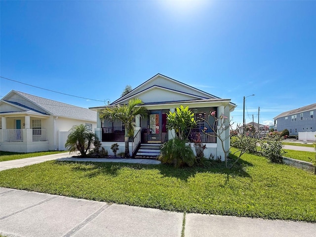 view of front of property featuring covered porch, driveway, and a front yard