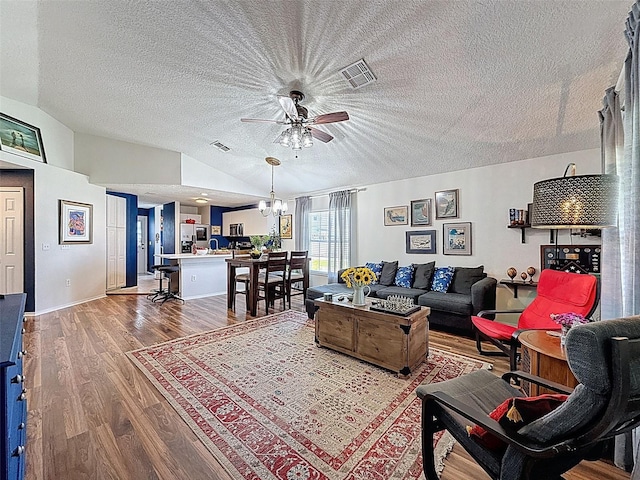 living area with ceiling fan, wood finished floors, a textured ceiling, lofted ceiling, and a chandelier
