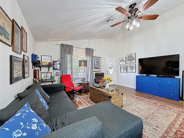 living area featuring vaulted ceiling, wood finished floors, a textured ceiling, and ceiling fan