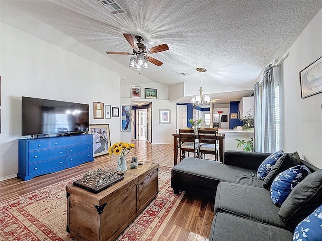 living room with vaulted ceiling, a chandelier, wood finished floors, ceiling fan, and a textured ceiling