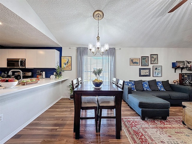 dining room with a chandelier, a textured ceiling, dark wood-style flooring, and ceiling fan