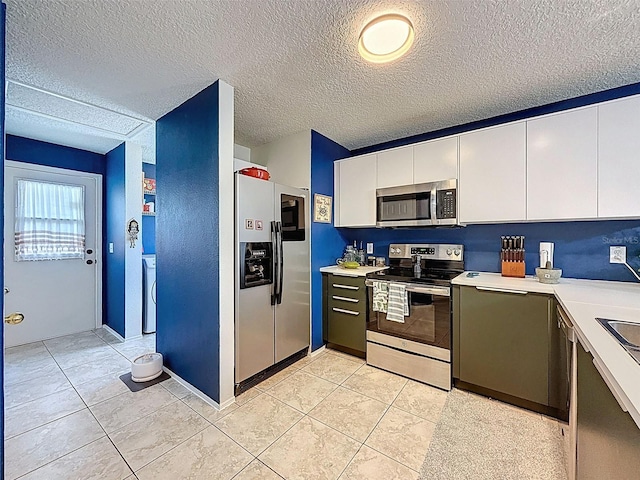 kitchen featuring appliances with stainless steel finishes, light countertops, white cabinets, light tile patterned floors, and a textured ceiling