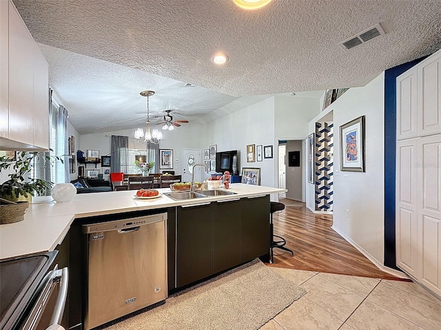 kitchen featuring appliances with stainless steel finishes, lofted ceiling, a peninsula, a textured ceiling, and light countertops