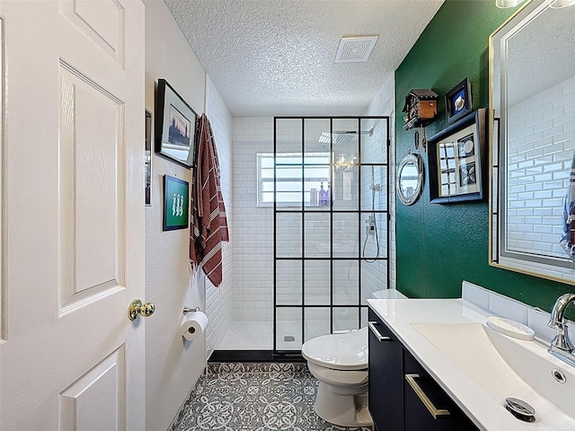 full bath with a stall shower, vanity, a textured ceiling, and tile patterned flooring