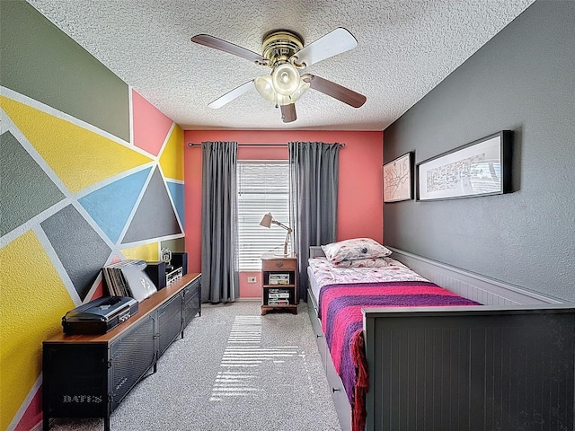 bedroom with a textured ceiling, a textured wall, carpet floors, and ceiling fan