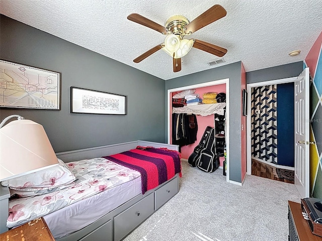 carpeted bedroom with a textured ceiling, a closet, and a ceiling fan
