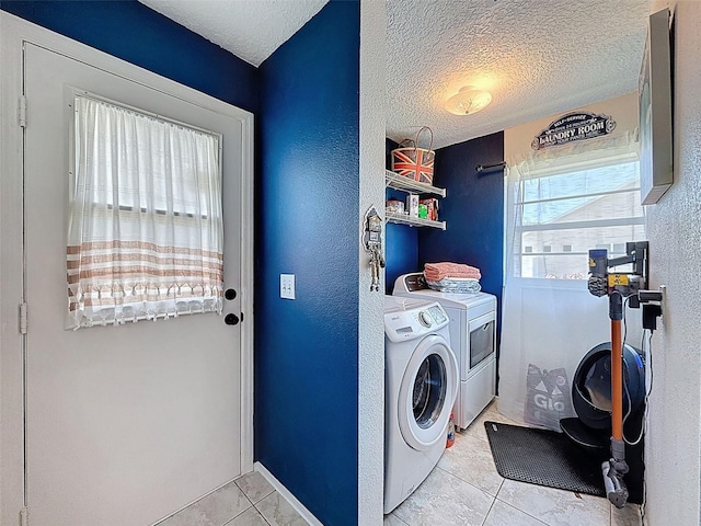 laundry room featuring light tile patterned floors, washer and clothes dryer, a textured ceiling, and a textured wall