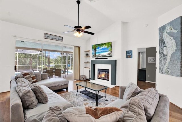 2454 Shadecrest Rd, Land O Lakes, FL 34639 - living room featuring a ceiling fan, high vaulted ceiling, a glass covered fireplace, and wood finished floors