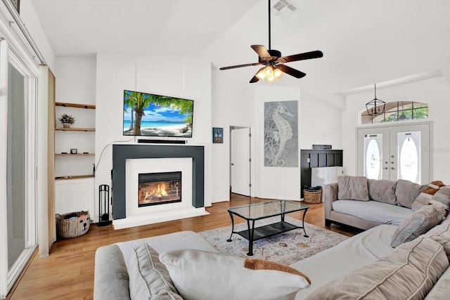 2454 Shadecrest Rd, Land O Lakes, FL 34639 - living area with light wood-type flooring, a glass covered fireplace, ceiling fan, french doors, and high vaulted ceiling