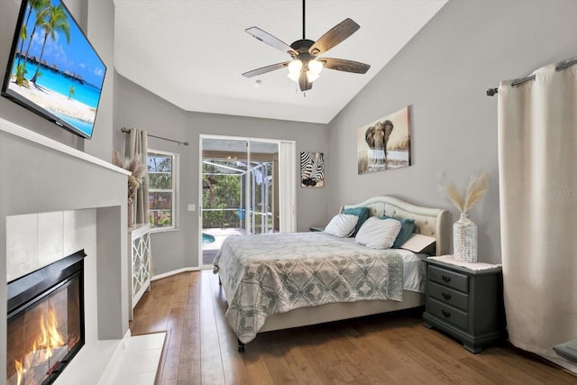 2454 Shadecrest Rd, Land O Lakes, FL 34639 - bedroom with access to exterior, a tiled fireplace, wood finished floors, vaulted ceiling, and a ceiling fan