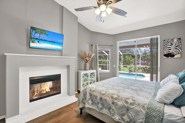 2454 Shadecrest Rd, Land O Lakes, FL 34639 - bedroom with access to exterior, wood finished floors, a ceiling fan, a tiled fireplace, and vaulted ceiling