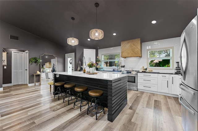 1313 W Carissa Ct, Tampa, FL 33604 - kitchen with appliances with stainless steel finishes, light wood-style flooring, a kitchen bar, white cabinetry, and a center island with sink