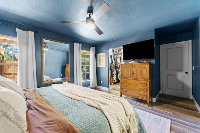 1313 W Carissa Ct, Tampa, FL 33604 - bedroom featuring multiple windows, wood finished floors, a textured ceiling, a walk in closet, and ceiling fan