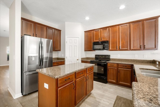 11132 Creek Haven Dr, Riverview, FL 33569 - kitchen featuring black appliances, light stone countertops, a kitchen island, light wood-type flooring, and recessed lighting