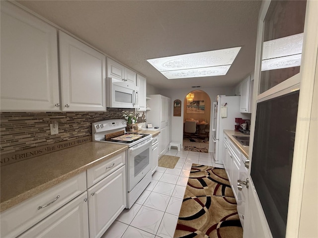 17569 SE 107th Ct, Summerfield, FL 34491 - kitchen featuring white appliances, white cabinetry, light tile patterned flooring, tasteful backsplash, and arched walkways